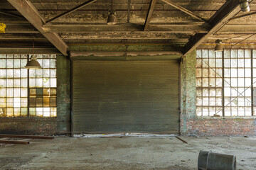 Brick wall, metal rolling garage door and frosted windows in an abandoned warehouse