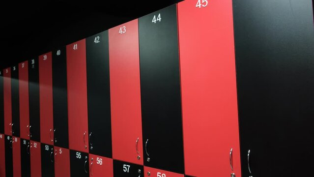 Public changing room in the gym. Closed shelves for storage. Cabinets with locks in red and black.