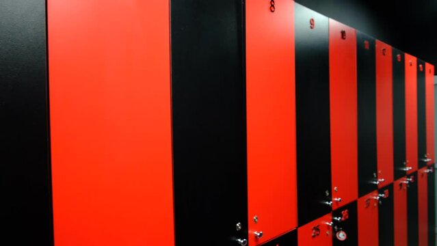Public changing room in the gym. Closed shelves for storage. Cabinets with locks in red and black.