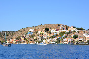 Fototapeta na wymiar Symi island with hills, town and waterfront with boats on the aegean sea