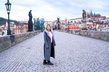 a pretty woman poses for the camera, in Prague on the Charles Bridge
