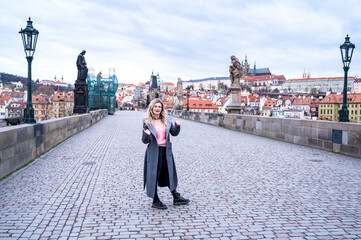 Fototapeta na wymiar beautiful woman posing on the Charles Bridge on the background of Prague Castle 