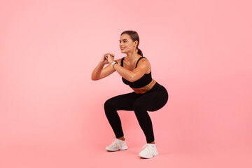 Fototapeta na wymiar Beautiful Sporty Young Woman Doing Deep Squat Exercise Over Pink Background