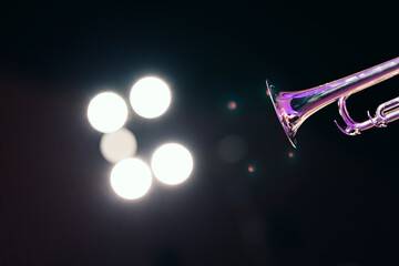 A shiny trumpet bell against bright stage lights during a solo of a jazz concert