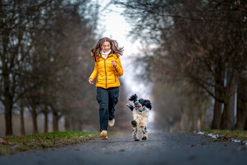 a happy teenager with a dog runs along an alley among the trees. english setter