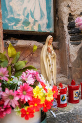 Christian votive chapel detail; in the foreground a plastic little statue of Holy Mary.