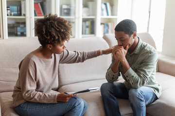 Young african woman psychologist consoling upset man