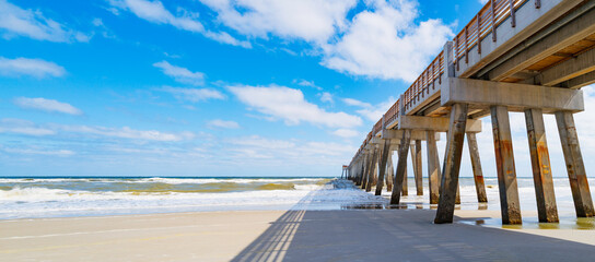 Seascape with sunny white sand beach, cloudy blue sky, shadows, and JAX  Beach Fishing Pier in Jacksonville, North Florida, USA © Naya Na
