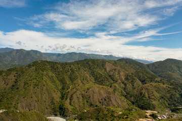 Aerial view of Mountains covered rainforest, trees and blue sky with clouds. Philippines.