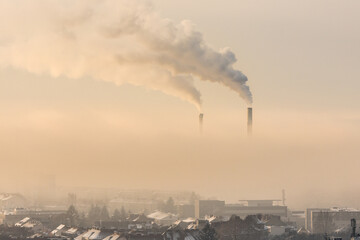 Smoking industrial chimneys emitting fine dust and carbon dioxide over Graz in Austria on a foggy winter morning