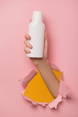 A woman hand holds a white bottle of shampoo. Template blank copyspace.