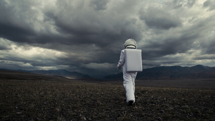 An astronaut explores an unknown red planet. Cloudy sky and mountains in the background.