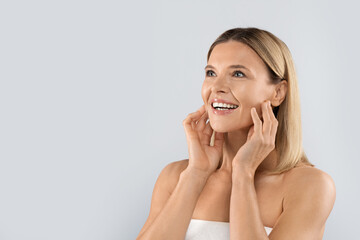 Happy adult blonde woman enjoying her new face, copy space