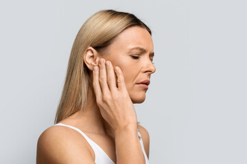 Fototapeta premium Woman having ear pain, touching her painful head, copy space