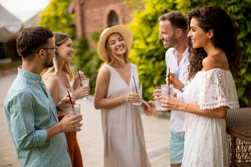 A group of young people gather outdoors to enjoy each other's company and refreshing glasses of lemonade