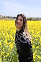 Naklejka na ściany i meble Happy beautiful young woman in yellow canola field.