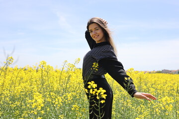 Happy beautiful young woman in yellow canola field.