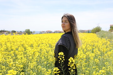 Naklejka na ściany i meble Smiling beautiful woman in yellow field. Flowers, spring and fresh air concept.