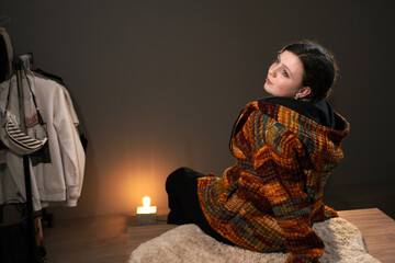 A cute girl in a knitted sweater of ocher autumn colors in a room. The warm light of an Edison lamp...