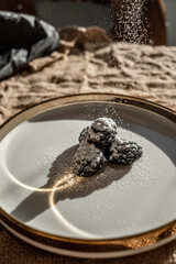Blackberry berries and the reflection of light in a dish with a golden border. Light pattern on the plate
