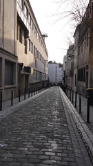 Une ruelle vide, urbaine, ancienne civilisation et historique, marche culturelle parisienne, haut bâtiment, caché dans l'ombre, ambiance mystérieuse et silencieuse, vide, personne ou peu de marcheurs
