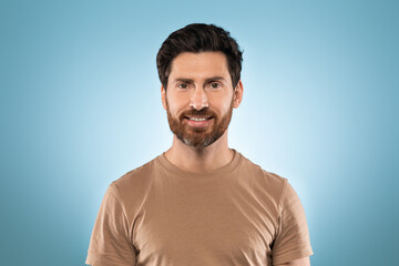 Obraz premium Portrait of happy handsome middle aged man posing isolated over blue studio background and smiling at camera