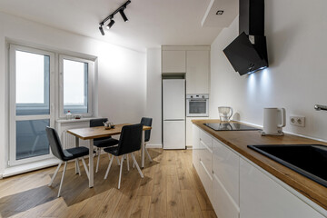 Modern interior of kitchen, wooden furnitureand stylish table and chairs. Spacious and luxurious space in apartment.