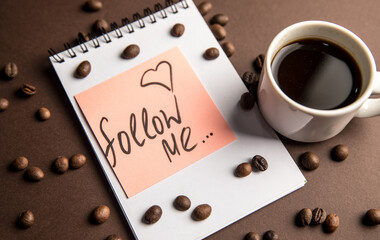 Notepad with the inscription follow me and a cup of coffee