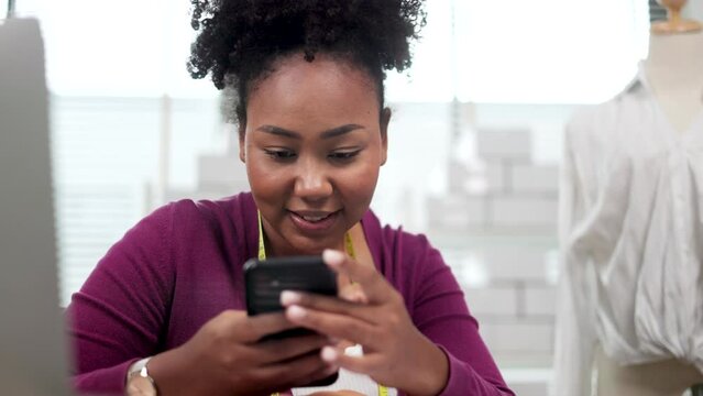 African american adult female woman fashion designer cloth tailor creative working for new collection.Happy online store owner preparing an order for shipping .