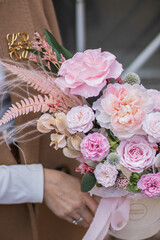 Beautiful spring flowers in box on woman hands. Preserved arrangement in grey round box. Women's day, mother's day, valentine's day.