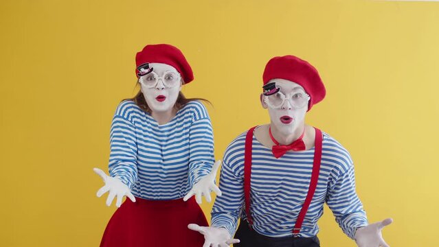 Young mimes heart-rendingly screaming emotionally showing their extreme interrogative surprise. Mimes playing funny performance on yellow background