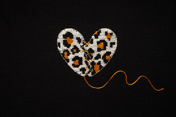 Broken heart leopard print embroidered on black fabric.
