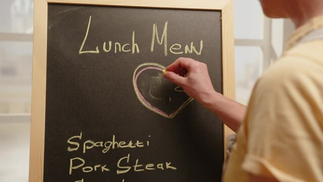 Price increase. Manager of street cafe changes price tag for menu on chalk blackboard.