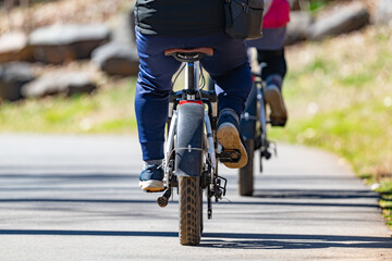 Naklejka premium Man riding an electric bike along a greenway trail in early spring