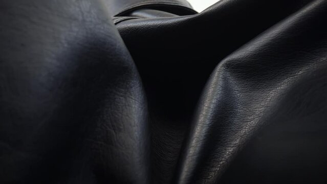 Macro shot black leather jacket clothing material. Slider dolly extreme close-up leather texture, camera glides over textured fabric and silver zipper. Studio shot laowa 24mm lens, white background