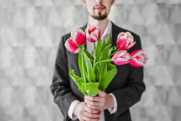 portrait of a man in a suit holding a bouquet of tulips in his hand close-up