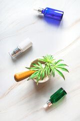 Cosmetic products on a marble table with a young sprout of hemp. Hemp products for body and face care.