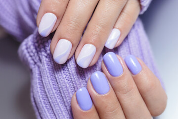 Female hands with a purple colour nails close-up. Nail design. Artistic manicure with a purple nail polish