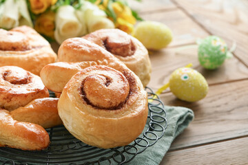 Easter breakfast Holliday concept. Easter bunny buns rolls with cinnamon made from yeast dough with orange glaze, easter decorations, colored eggs on old wooden background. Easter Holliday card.