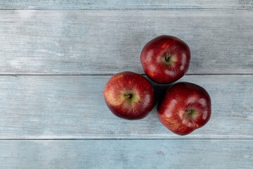 Three red apples above dark blue moody background flat lay