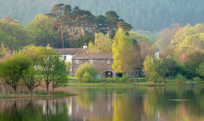 Restful image of a farmhouse on a still dawn by the lake
