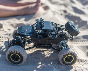 a radio-controlled model of an SUV smeared in sand outdoor.