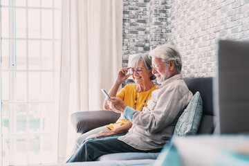 Elderly grandfather and grandmother spend time having fun using smartphone apps, middle-aged wife enjoy online entertainments, taking selfie with old husband, older generation and modern tech concept.