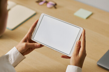 Closeup young woman holding tablet with white screen mockup at workplace