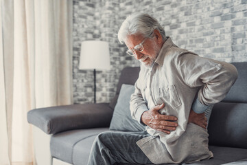 Upset senior elder man feel sudden back pain muscles ache tension injury sitting at home, sad old...