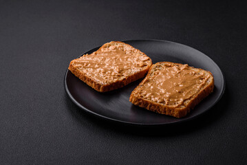 Nutritious sandwich consisting of bread and peanut butter on a black ceramic plate
