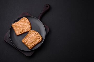 Nutritious sandwich consisting of bread and peanut butter on a black ceramic plate
