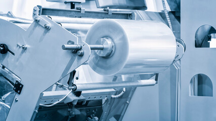 Automatic polyethylene plastic bag production machine with lighting effect. Close-up of the roller of the plastic bag production machine in the light blue scene. product packaging concept