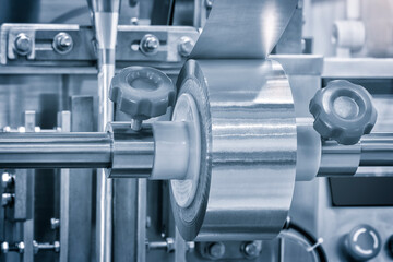 Automatic polyethylene plastic bag production machine with lighting effect. Close-up of the roller of the plastic bag production machine in the light blue scene. product packaging concept