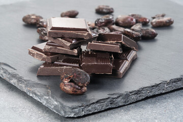 Broken dark chocolate and cocoa beans on a table